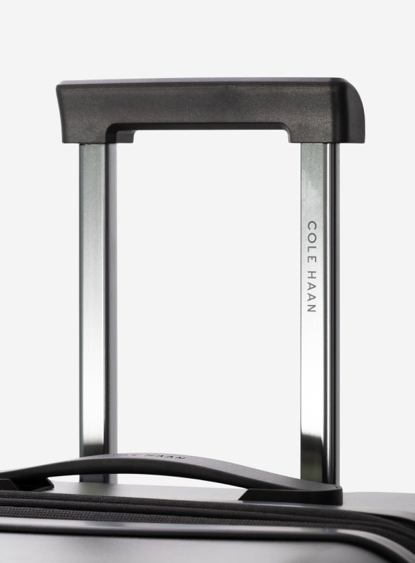 Close-up of a black Cole Haan suitcase handle on a white background