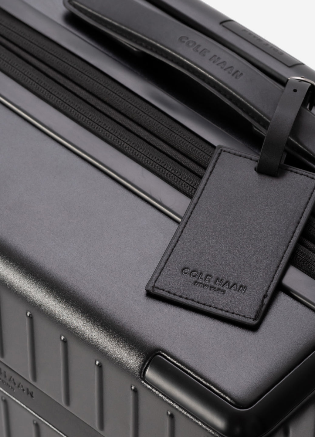 Black suitcase with a matching luggage tag on a black background