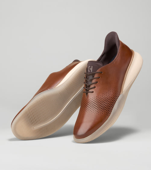 Brown leather shoes with white soles on a light gray background