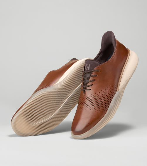Brown leather shoes with white soles on a gray background