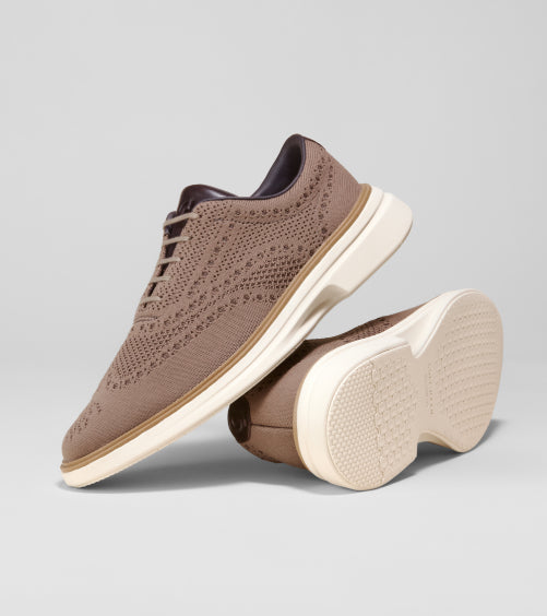 Men's brown oxfords with white soles on a gray background