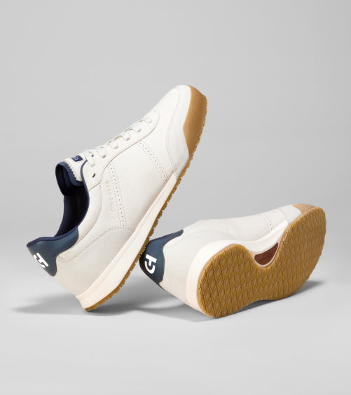 Men's white sneakers with brown soles on a gray background