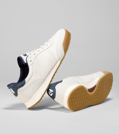 Pair of white sneakers with brown soles on a gray background