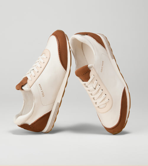 Pair of white sneakers with brown soles on a light gray background