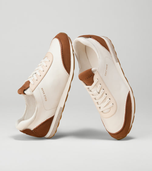 Pair of white sneakers with brown accents on a light gray background