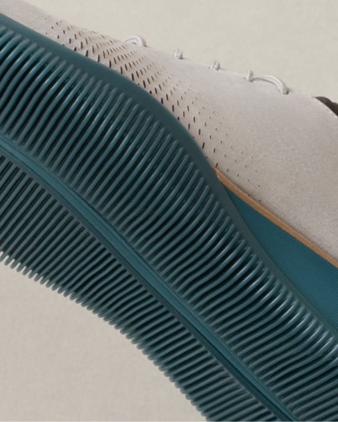 Close-up of a teal shoe sole on a light oxford with a white background