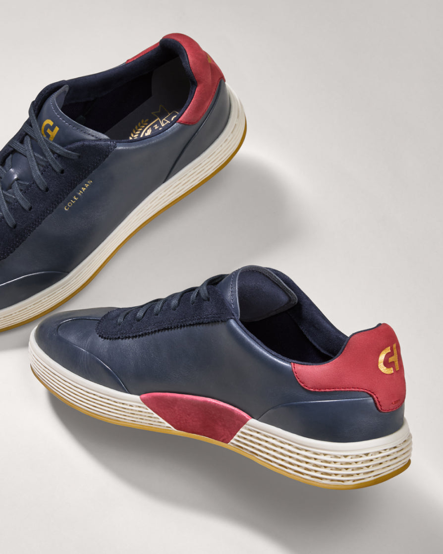 Navy and red sneakers with a visible brand logo on a light gray background