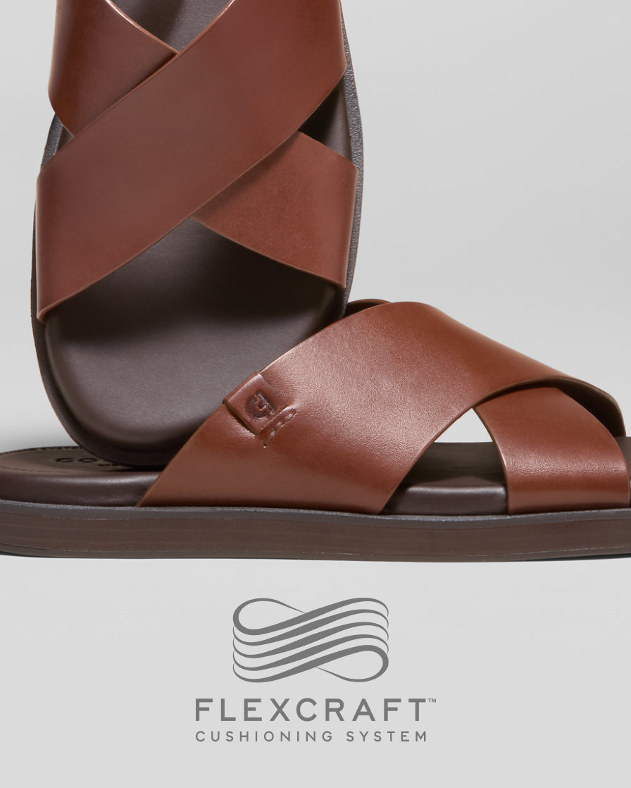 Brown sandal with criss-cross straps on a light gray background, featuring Flexcraft cushioning system logo.