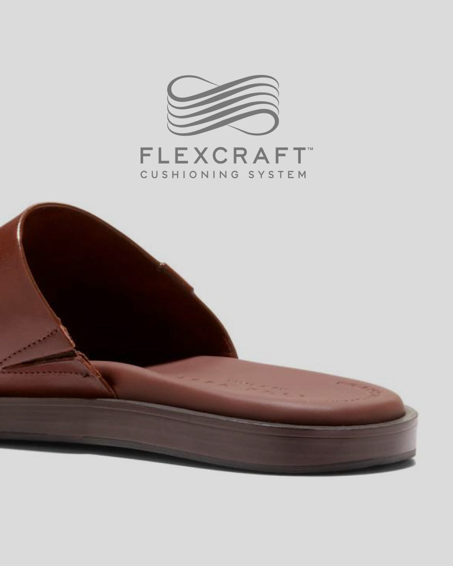 Brown sandal with Flexcraft cushioning system logo on a light gray background