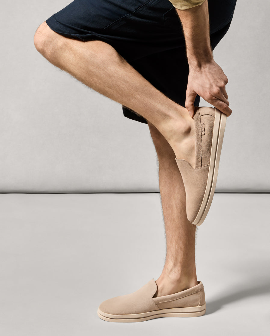Person wearing beige slip-on shoes on a plain background