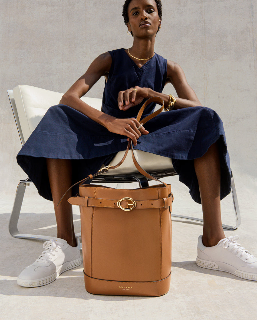 Woman sitting on a chair with a brown leather bucket bag in front of her