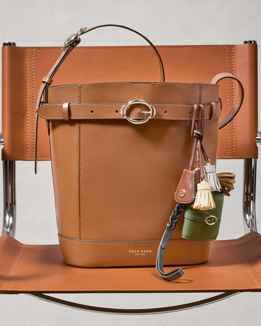 Brown leather handbag with decorative charm on a light gray background