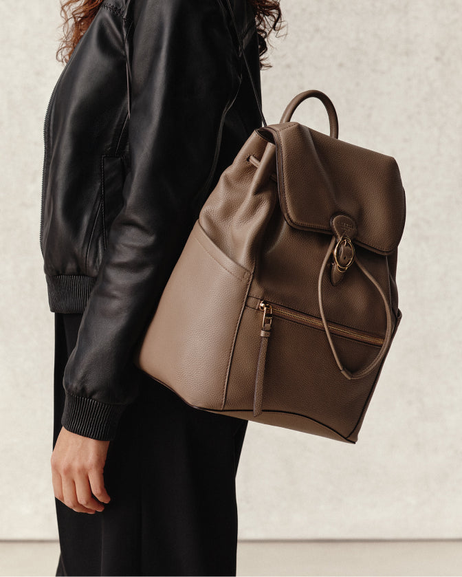 Women in black leather coat with light brown leather bag