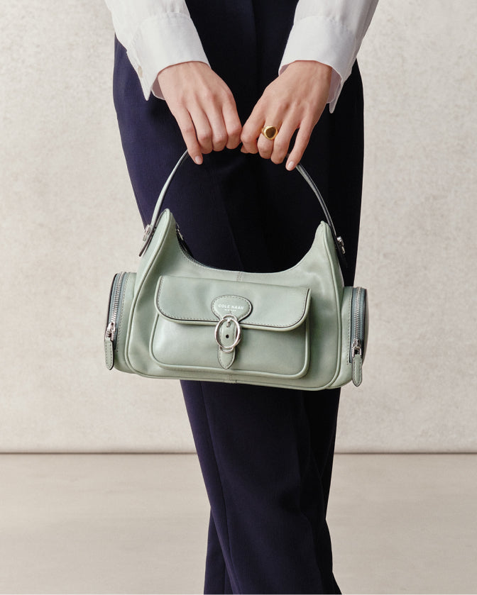 Person holding a light green handbag against a neutral background