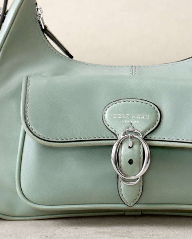 Light green handbag with a silver buckle on a light gray background
