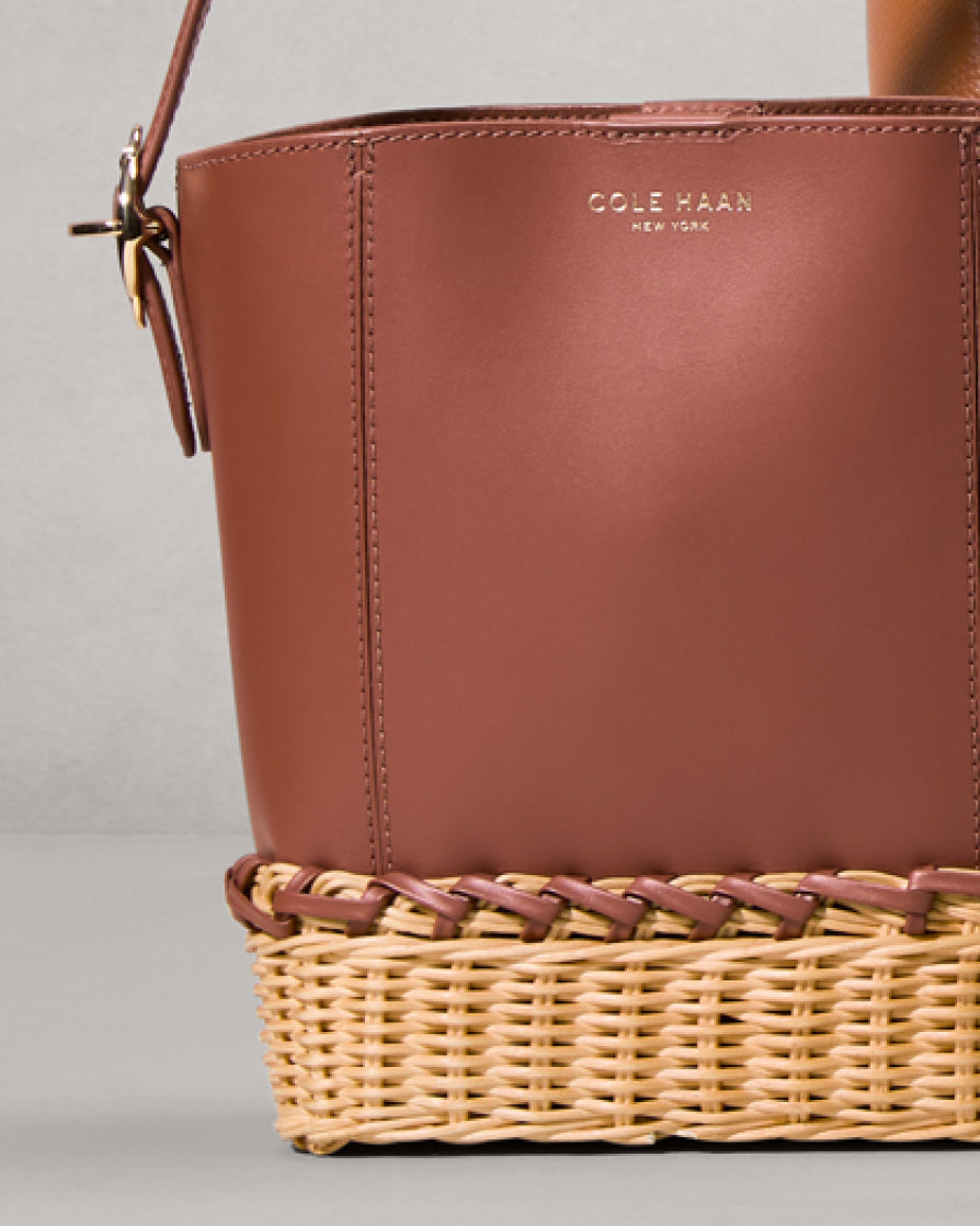 Brown leather handbag with wicker base on a gray background