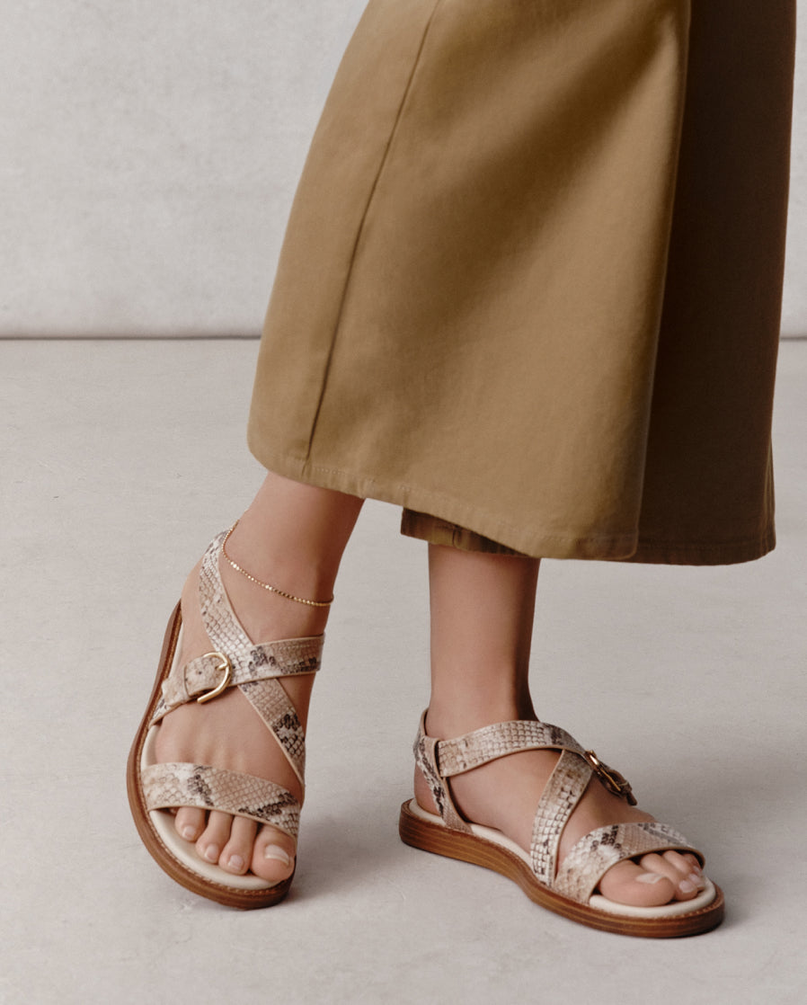 Person wearing snake print sandals with a neutral background