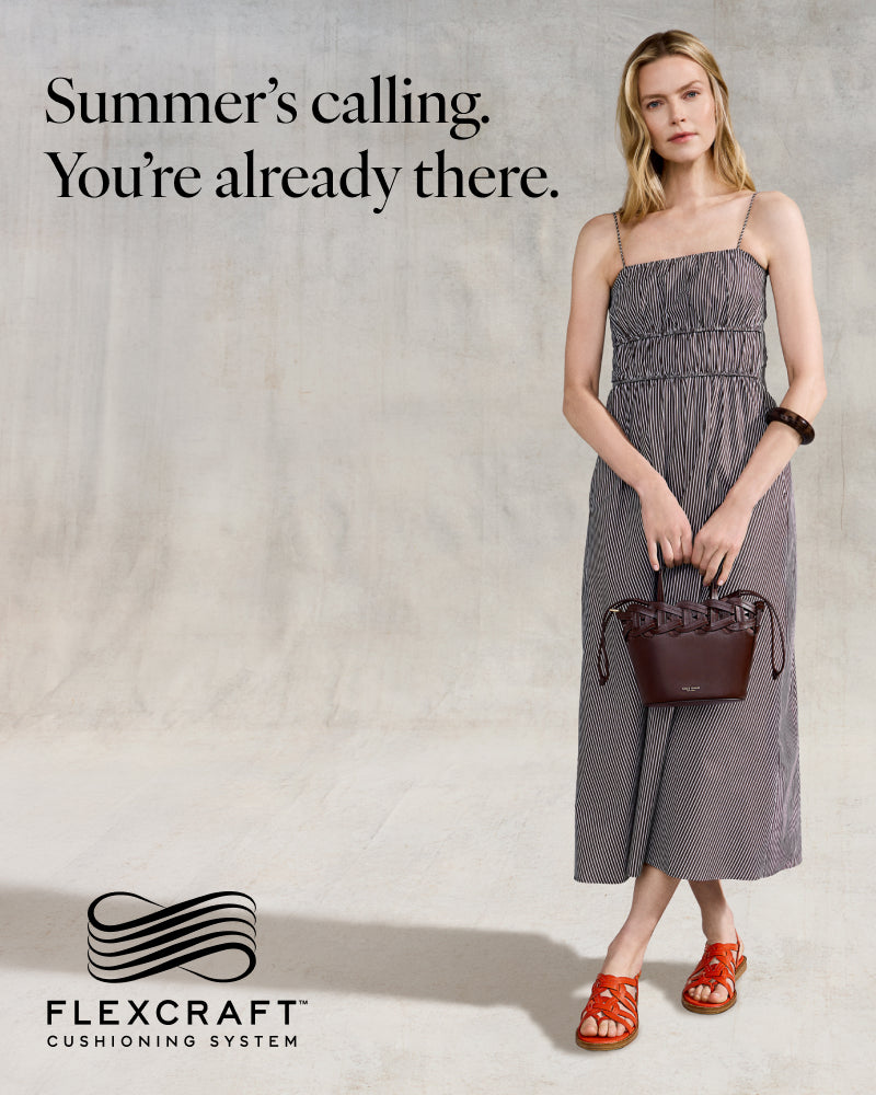 Woman in a gray dress holding a brown handbag with 'Flexcraft' branding and text on a neutral background.