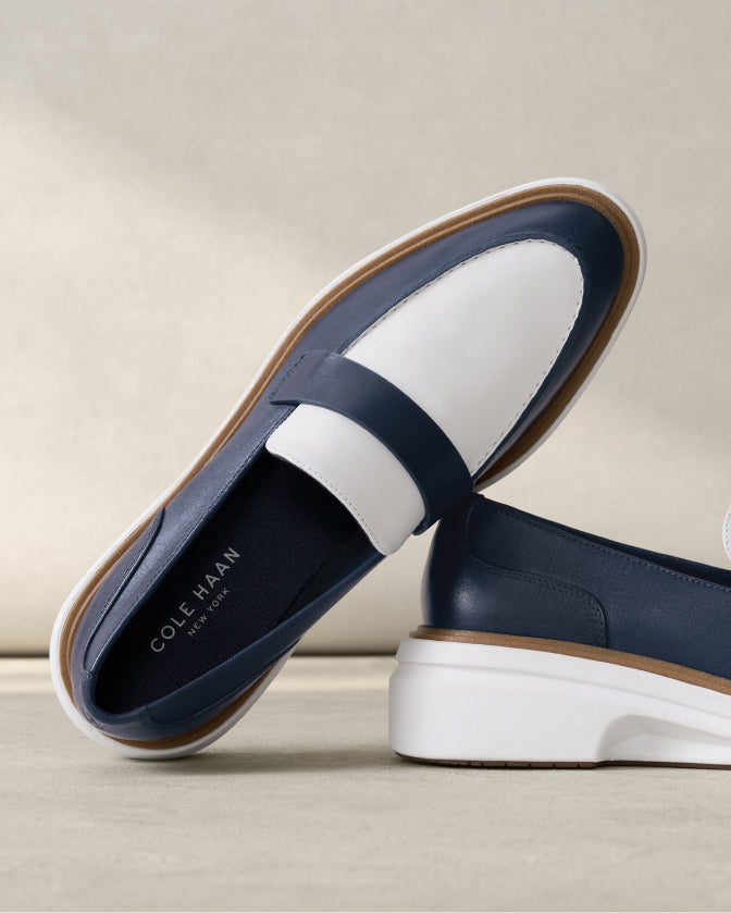 Navy loafers with white soles on a beige background