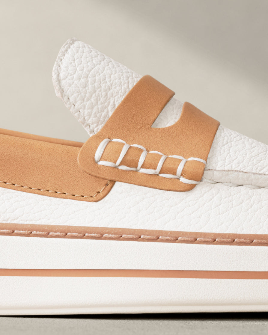 Close-up of a white loafer with beige accents on a light background