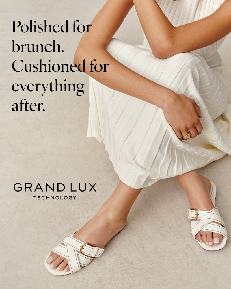 Woman wearing white sandals on a neutral background.