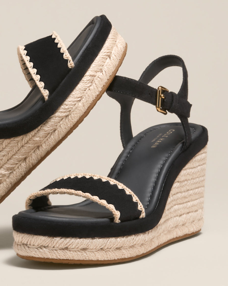 Black wedge sandals with jute straps on a beige background