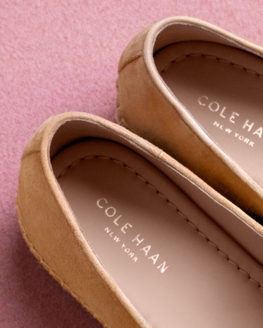 Close-up of tan Cole Haan shoes on a pink background