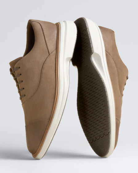Pair of brown shoes with white soles on a light gray background