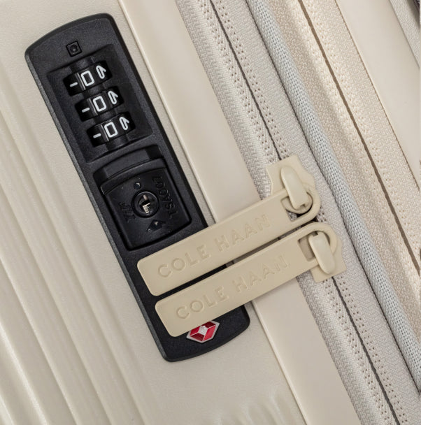 Close-up of a Cole Haan suitcase with a combination lock and tags.
