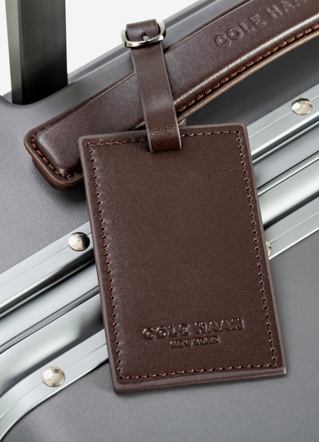 Brown leather luggage tag attached to a gray suitcase