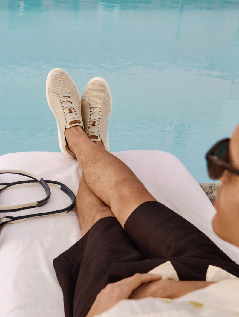 Man wearing beige sneakers by the pool