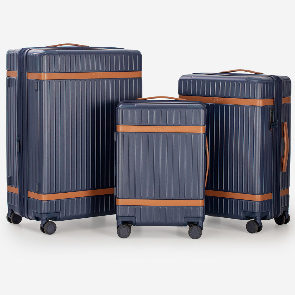 Set of three navy blue suitcases with brown accents on a white background