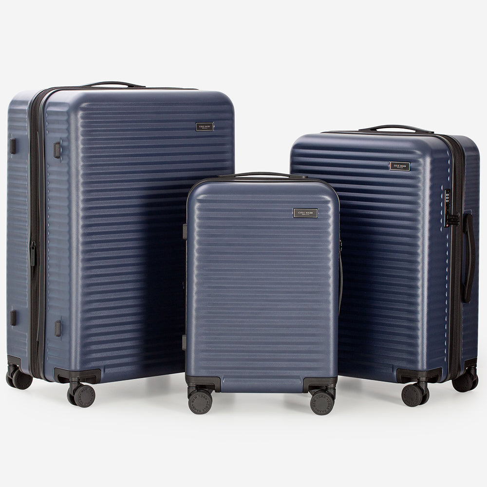 Set of three navy blue suitcases of different sizes on a white background