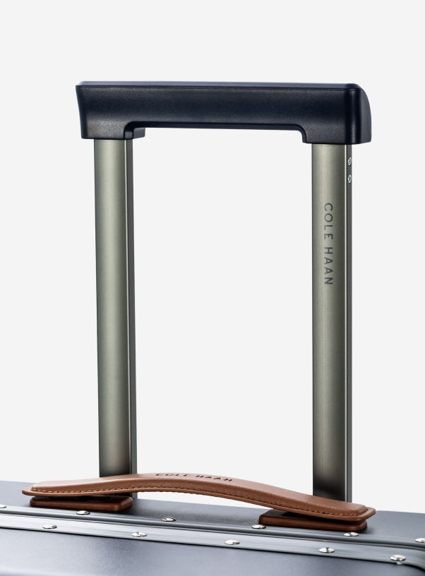 Cole Haan luggage handle on a suitcase with a white background
