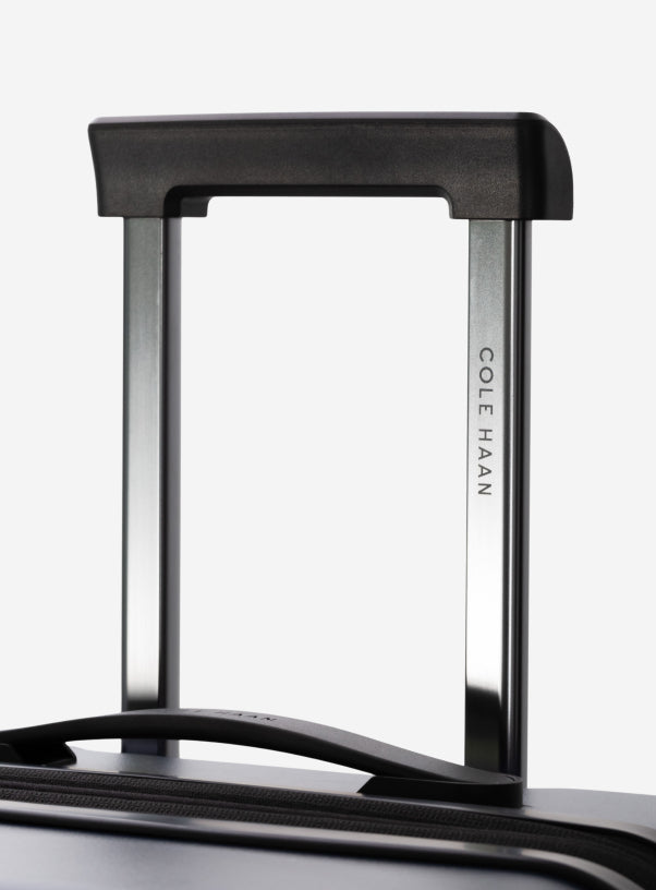 Close-up of a navy blue Cole Haan suitcase handle on a white background