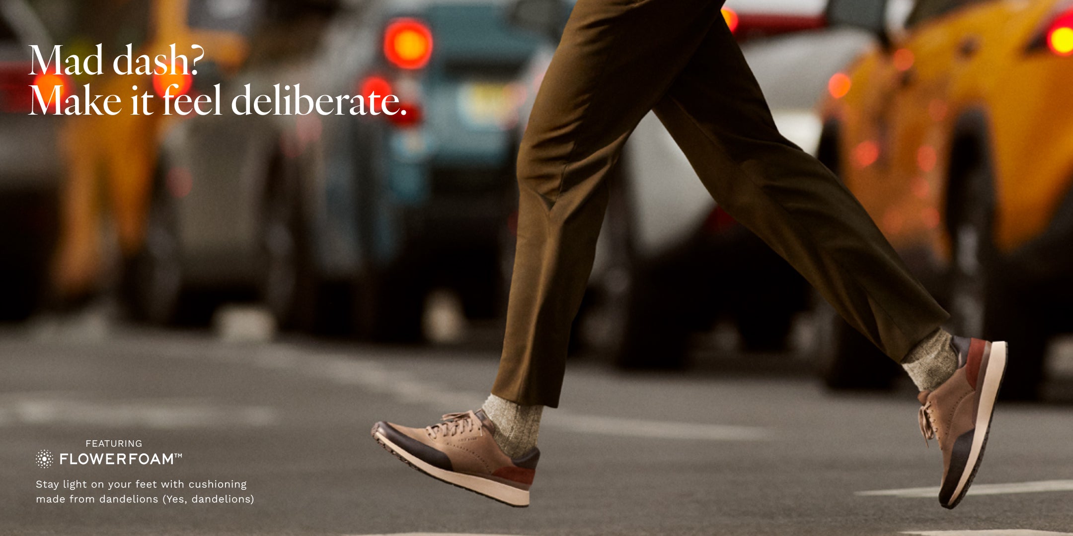 Person walking on a city street with blurred traffic in the background, wearing brown shoes.