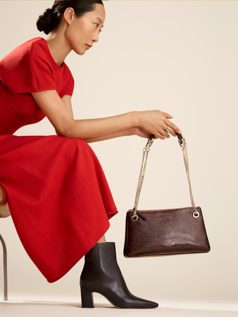 Woman wearing brown booties holding brown handbag