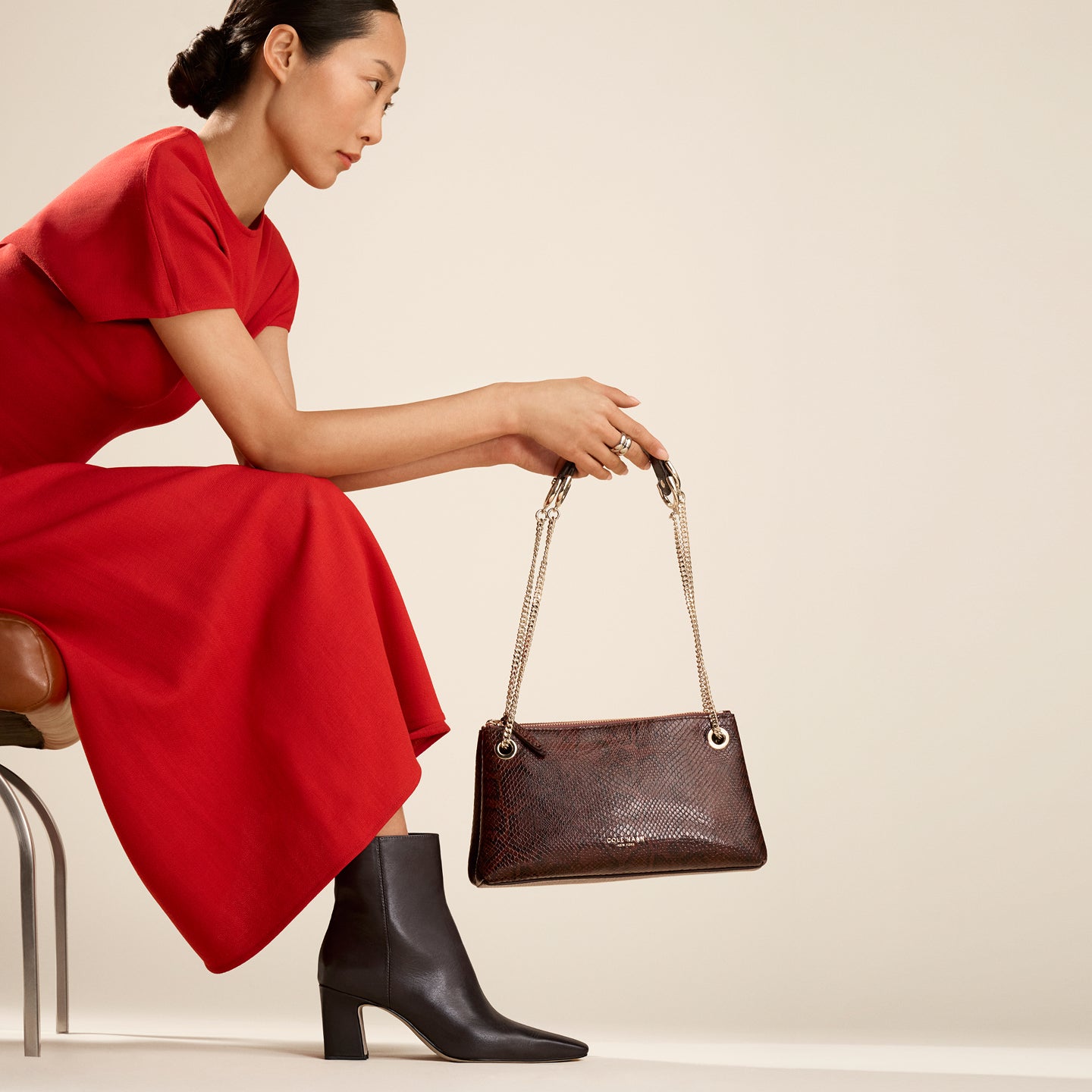 Woman wearing brown booties holding brown handbag