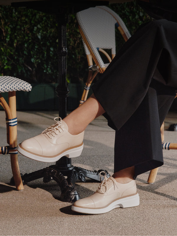 Person wearing beige shoes with white soles in an outdoor setting.